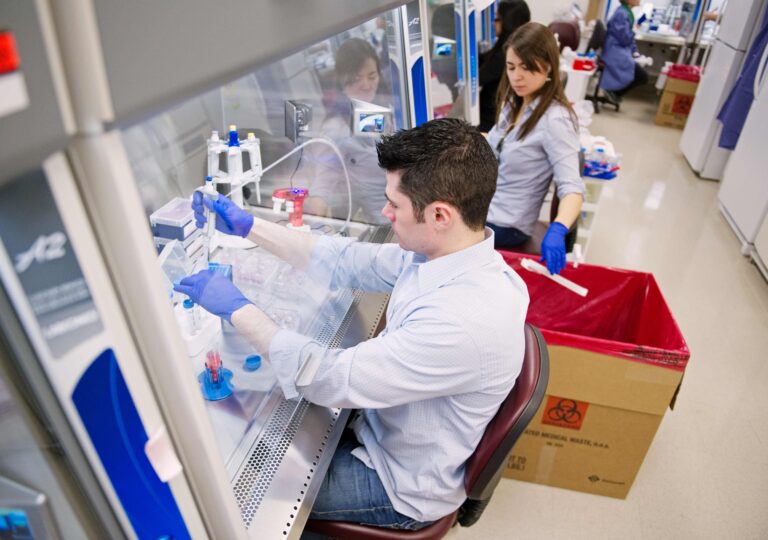 An over-the-shoulder shot focuses on a young student Ryan Mulhern who's examining cell samples alongside a fellow student at the Center for Regenerative Medicine. Photo by Jackie Riccardi for Boston University Photography.