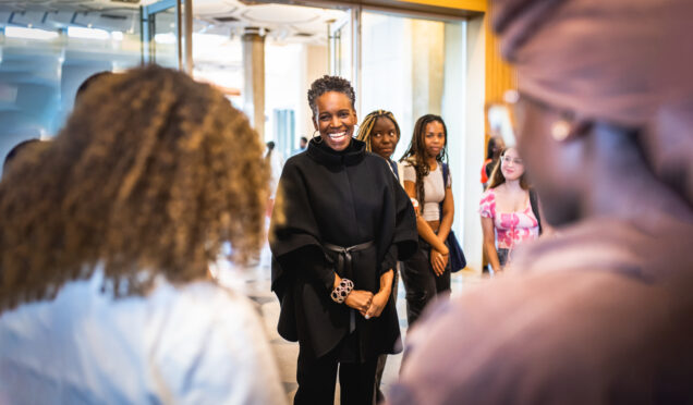 Dr. Melissa L. Gilliam, meets with students at the Howard Thurman Center. She Has a bright smile on her face as she engages questions and queries from a diverse audience in the hallway. 
