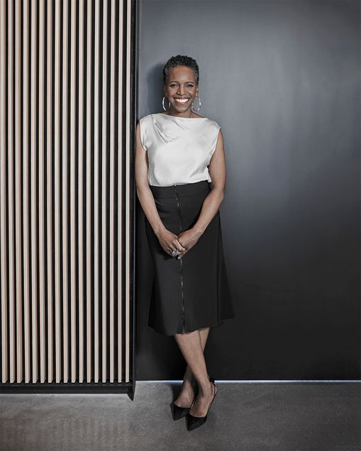 Boston University President Melissa Gilliam leaning against a slatted wood accent wall