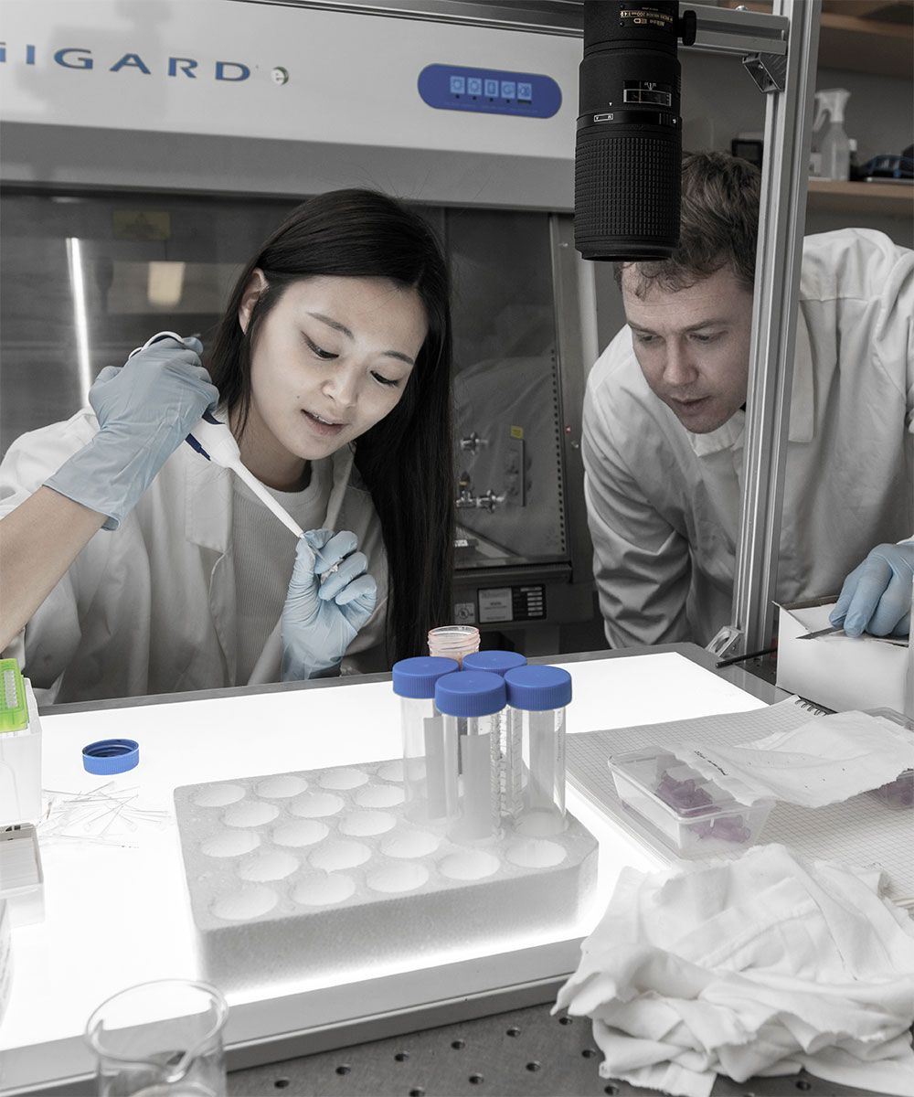 Two students working with a pipette in a laboratory setting