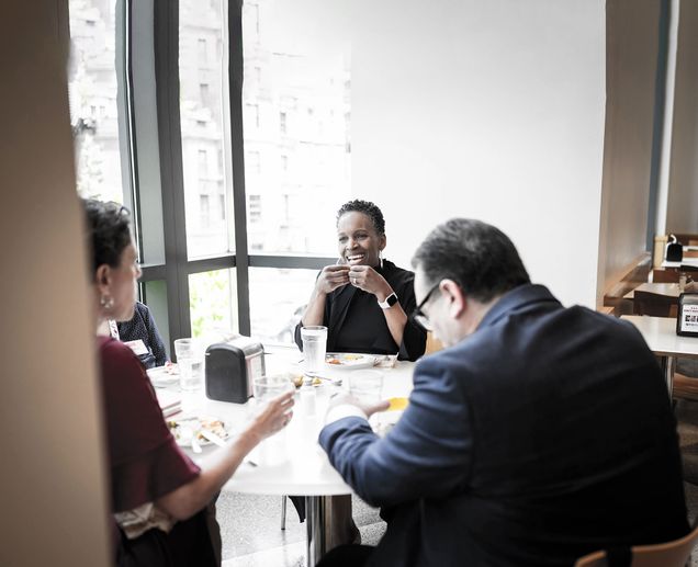 President Melissa Gilliam sitting around a round table and eating with a small group of staff from the Boston University Libraries and the Gotlieb Center