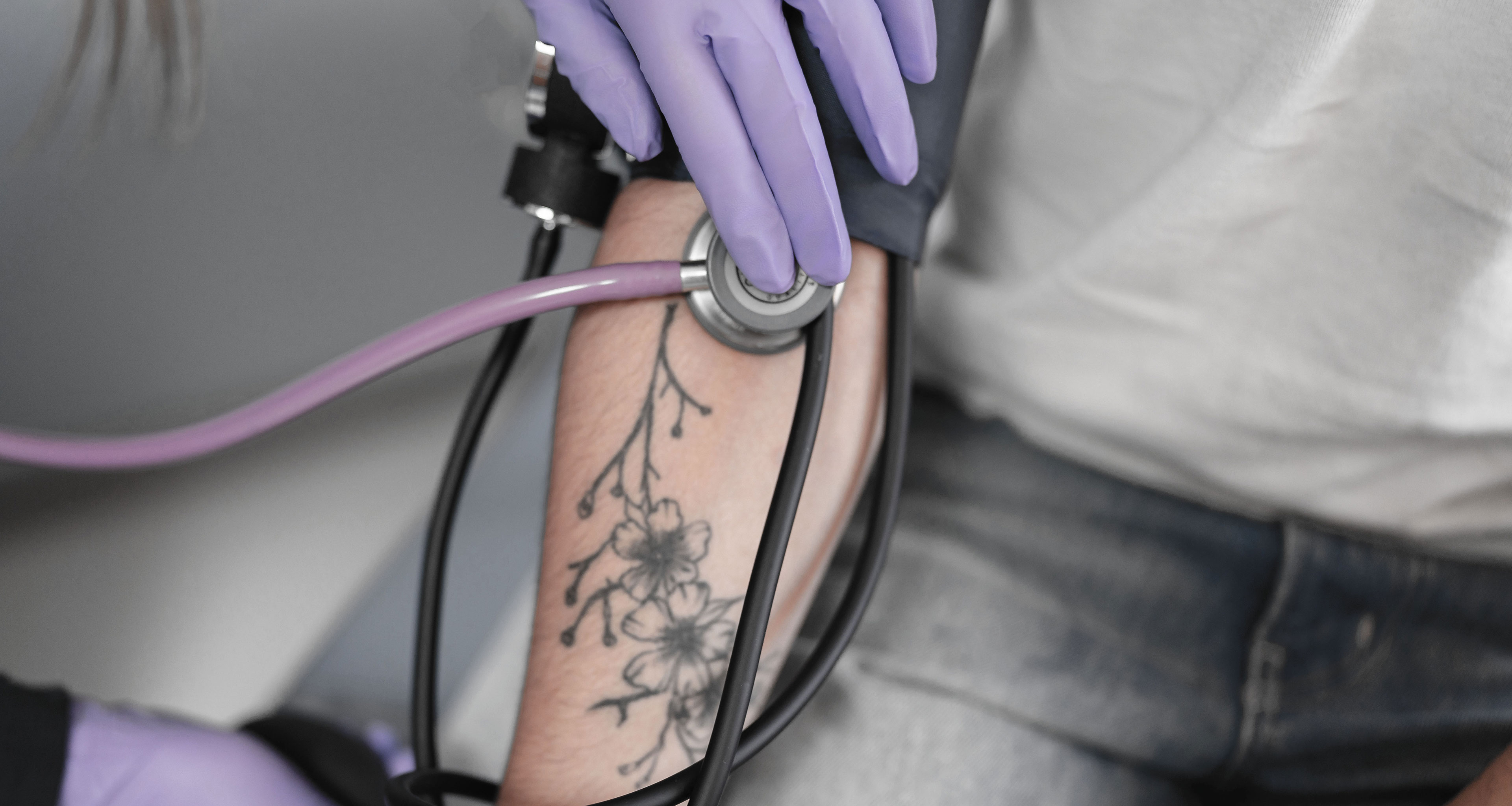 An arm with a floral tattoo getting a blood pressure reading from staff at Boston University's Student Health Services