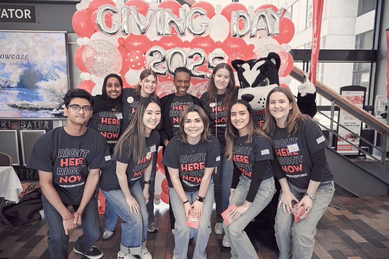 A group of students posing for a photo in front of a balloon arch with President Melissa Gilliam at Giving Day 2025
